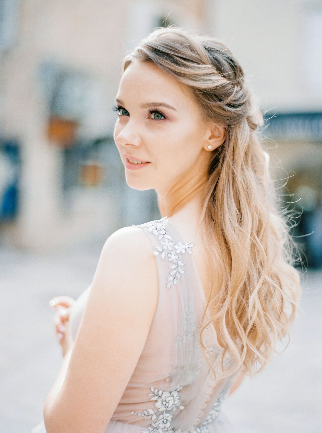 Smiling bride glancing back over her shoulder, long waves falling over a beaded tulle gown