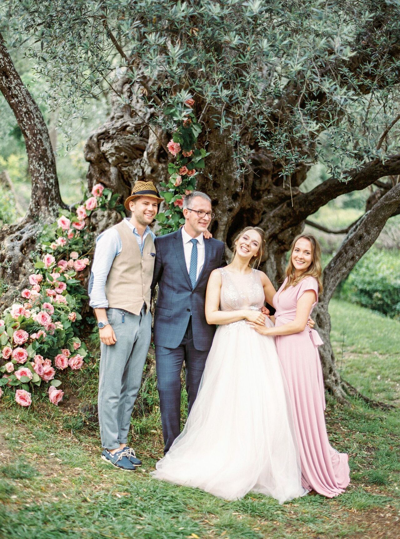Couple laughing with friends beneath a flowering olive tree