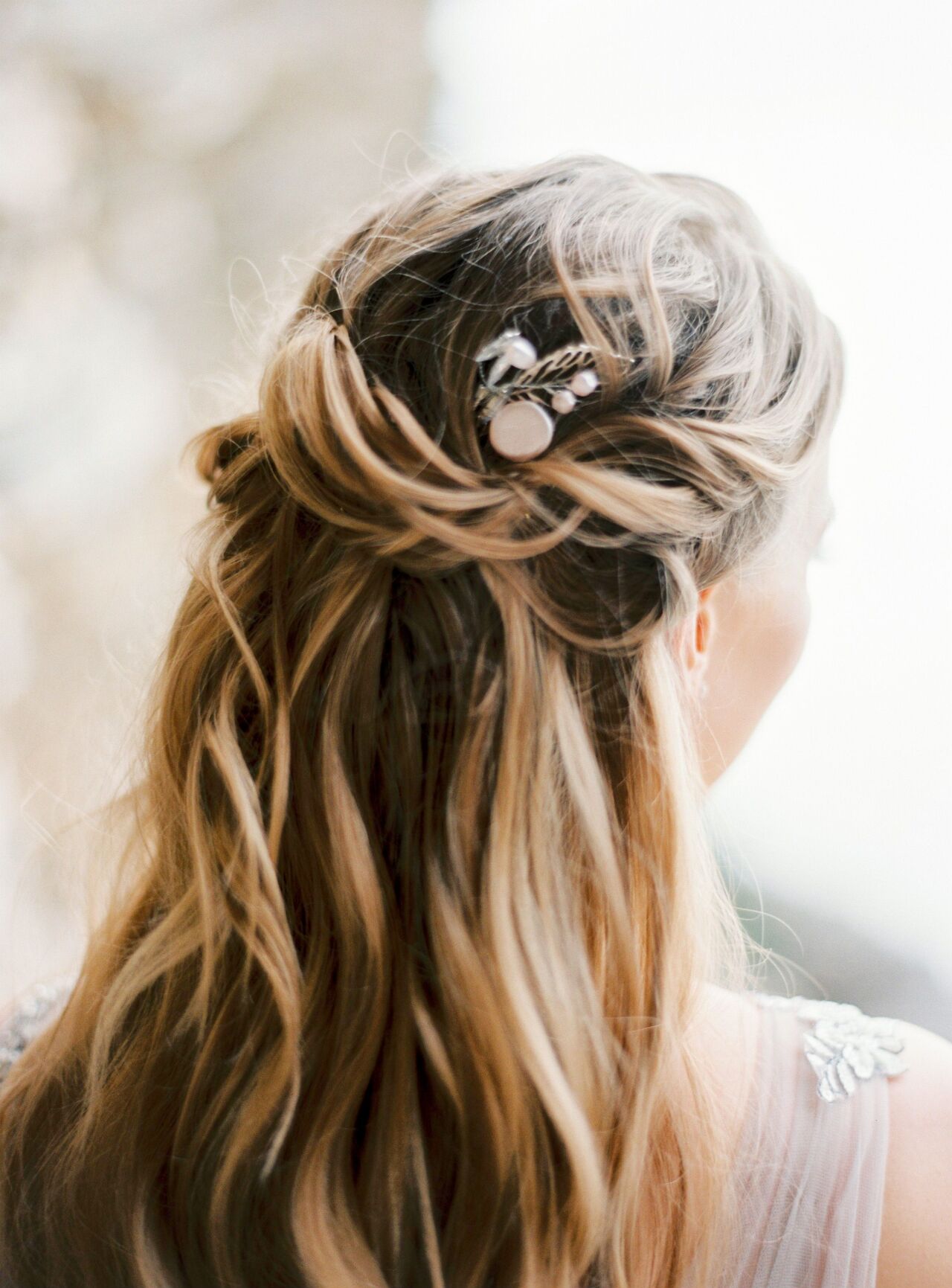 Bride's loose blonde waves pinned with a delicate floral hair clip