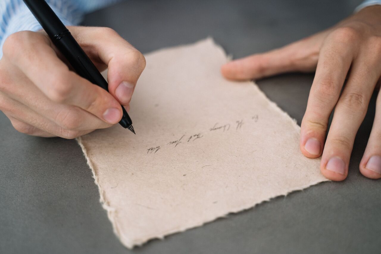 Hand writing a short letter on handmade paper