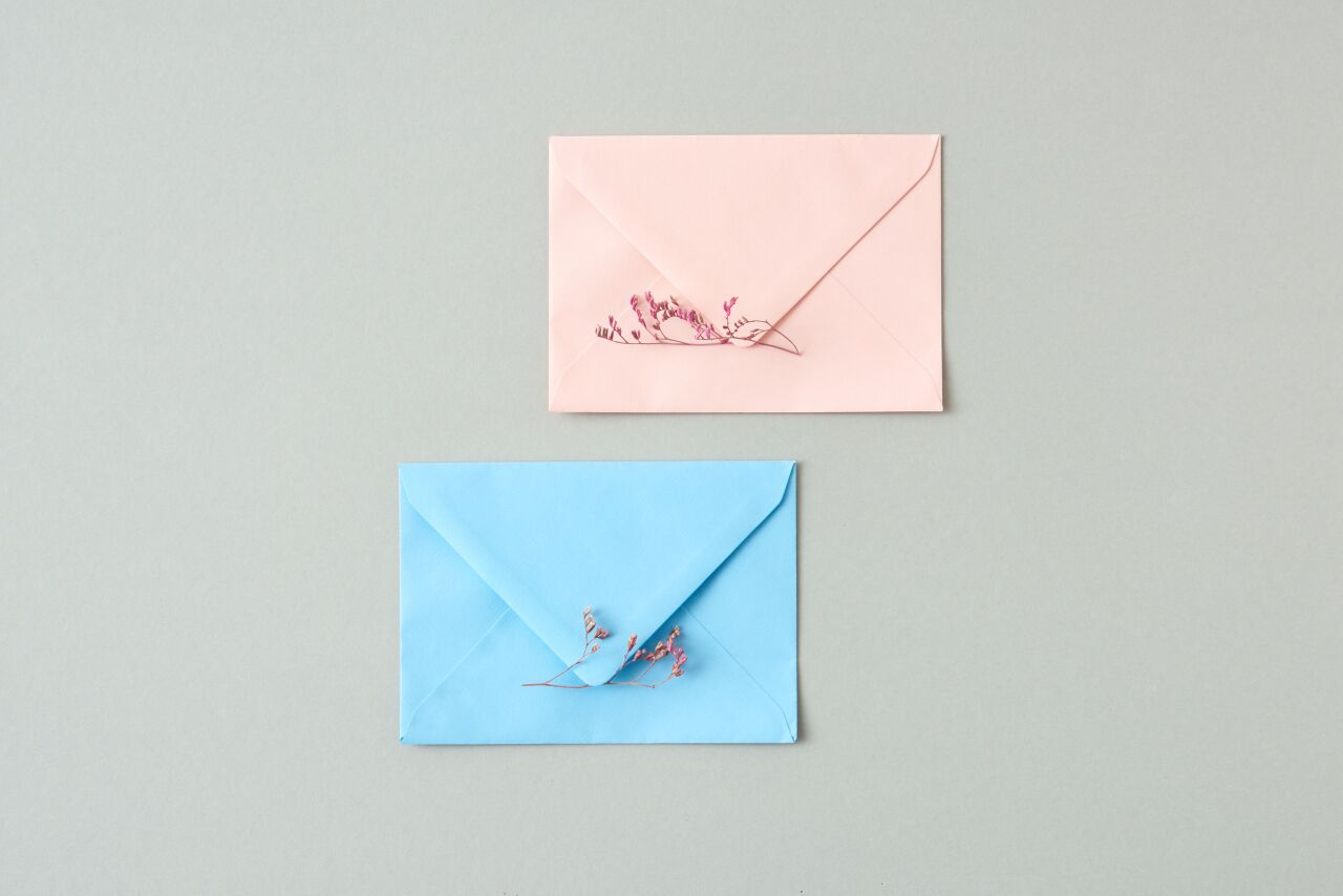 Blush and pale blue envelopes on a soft sage background